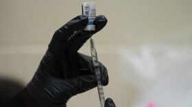A Scripps health official draws from a vile the COVID-19 vaccine prior to administering it to a patient at their new drive-thru vaccination site at the Del Mar Fairgrounds on Friday, Feb. 12, 2021 in Del Mar, Calif.