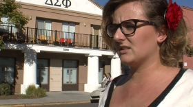 San Diego State University student Jordan Busse stands in front of the fraternity house balcony where she says men waved sex toys at her and others marching to raise awareness about rape on campus, Nov. 24, 2014.