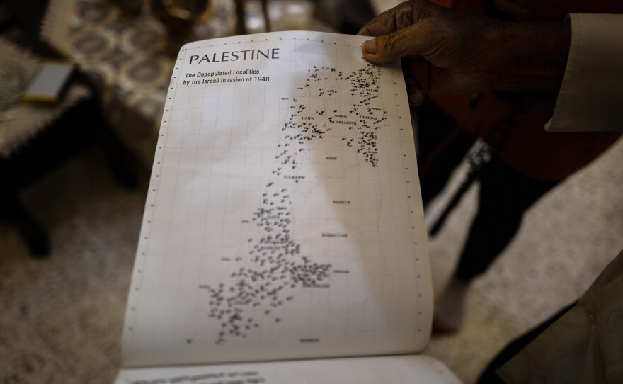 84-year-old Mohammed Suleiman Khader looks through an atlas of old Arab villages — searching for his.
