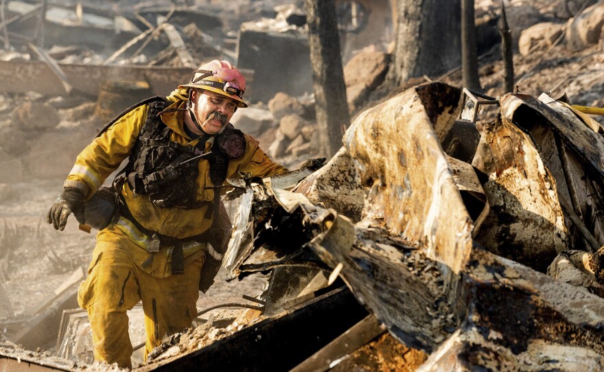 Firefighter Jesse Viescas searches through a residence at Cache Creek Mobile Home Estates where the Cache Fire leveled dozens of homes, Wednesday, Aug. 18, 2021, in Clearlake, Calif.