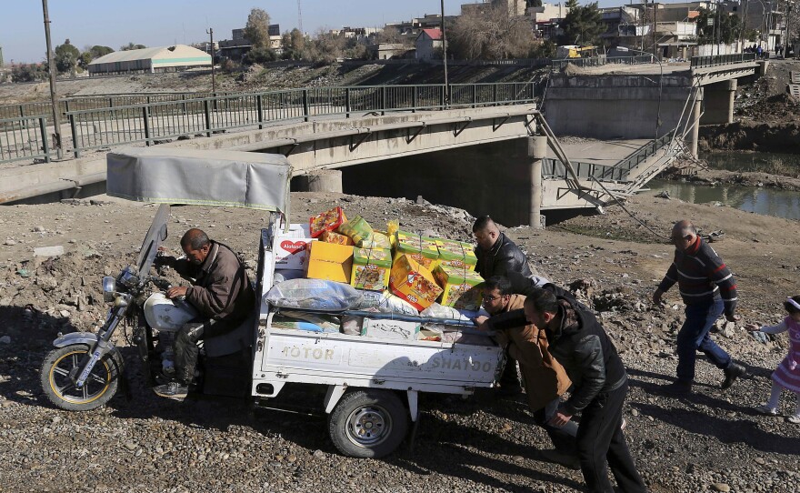 Men push a cart at a makeshift river crossing next to a bridge destroyed by Islamic State militants in Mosul, Iraq, on Thursday. The Iraqi forces have reclaimed much of eastern Mosul, but the Islamic State still controls much of the western side of the city.
