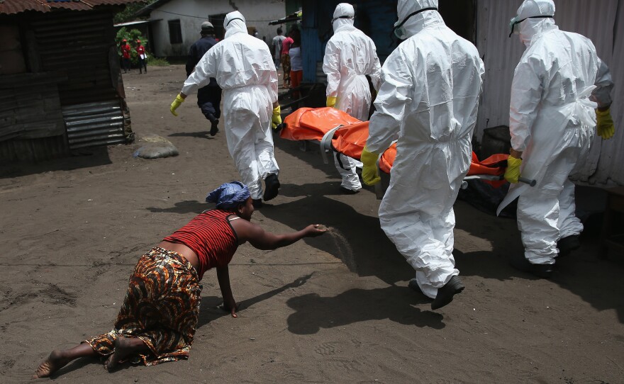 As an Ebola burial team takes Mekie Nagbe, 28, for cremation, her sister throws a handful of soil toward the body — a parting gesture.