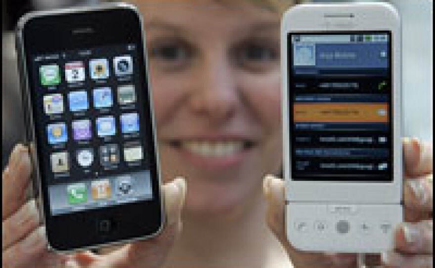 A woman presents the T-Mobile G1 (R) mobile device by Deutsche Telekom and the i-Phone 3G by Apple in March 2009 at the world's biggest high-tech fair, CeBIT in Hanover, central Germany.