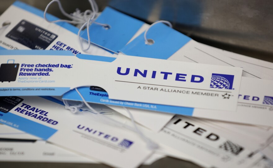 United Airlines baggage tags are displayed on a table at San Francisco International Airport. The carrier says it's starting a pilot program next month that will offer rapid coronavirus testing at the airport or via a self-collected, mail-in test ahead of their flight.