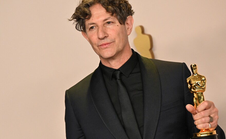 Jonathan Glazer poses in the press room with the Oscar for best international feature film for <em>The Zone of Interest.</em>
