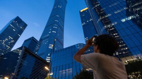 A passerby tries to take photo of the damage on the Citic Tower also known as Zun Tower in Beijing, China, Friday, June 26, 2026.