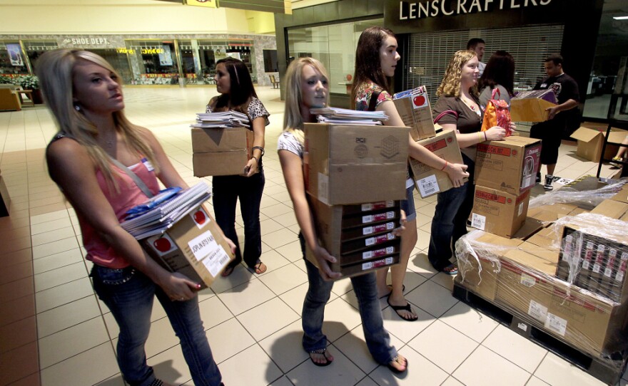 Students carry donated supplies to a classroom on the first day of school at a temporary high school in a converted big-box store in Joplin, Mo., last August. School started on time in the district nearly three months after an EF-5 tornado devastated much of the city and killed 161 people.
