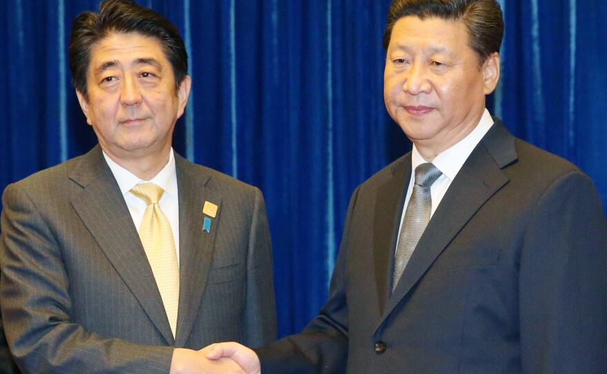 Japanese Prime Minister Shinzo Abe, left, and Chinese President Xi Jinping shake hands at the Great Hall of the People in Beijing Monday, prior to their first-ever talks.