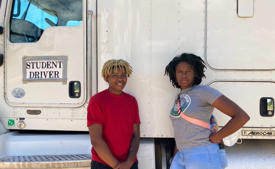 Amalya Livingston, right, poses in front of a truck at the DSC Training Academy on June 29, along with another student. Livingston says she faces sexism on the road but it doesn't deter her from driving.