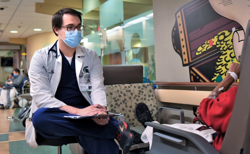 A medical student from the College of Osteopathic Medicine at Michigan State University consults with a patient in the hallway of the Sparrow Hospital ER.