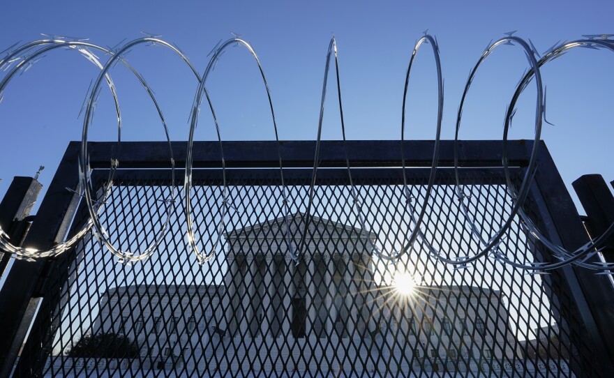 The Supreme Court is seen beyond a razor wire-topped fence at sunrise on March 8.