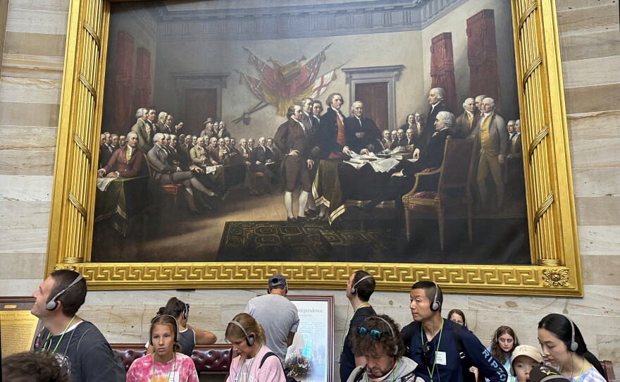 Tourists visit the U.S. Capitol appear under John Trumbull's larger-than-life painting depicting the moment the Declaration of Independence was presented to the Second Continental Congress.