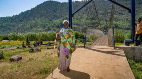 Naomi Nibishaka crosses the newly constructed pedestrian bridge over a river. She's on her way to see her son and grandchildren, who live in a settlement on the other side.