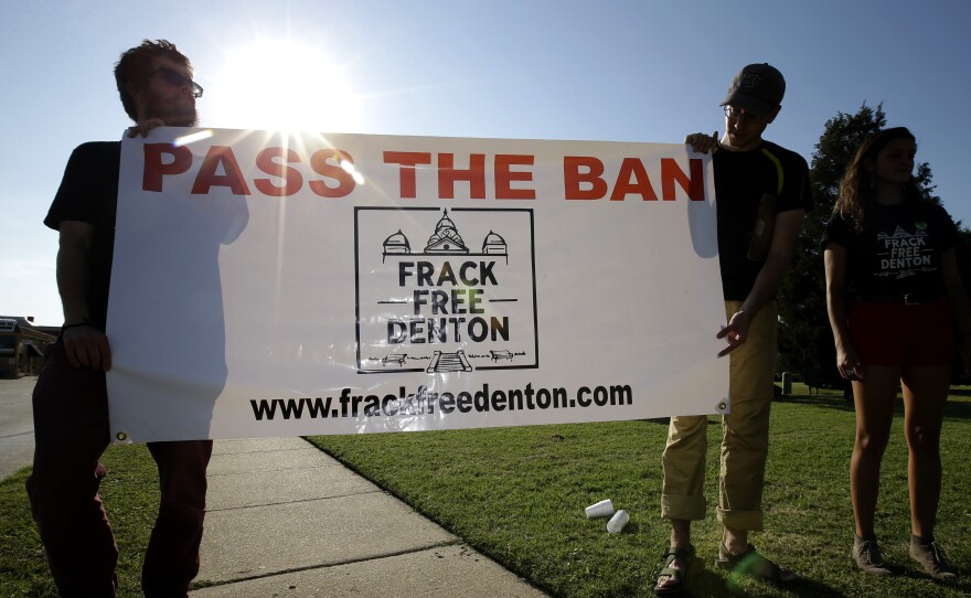 From left, Topher Jones, Edward Hartmann and Angie Holliday hold a campaign sign outside City Hall in Denton, Texas, on July 15, 2014. Voters in the college town approve a ban on fracking on Tuesday.