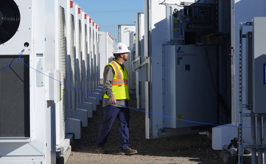 A worker does checks on battery storage pods at Orsted's Eleven Mile Solar Center lithium-ion battery storage energy facility Thursday, Feb. 29, 2024, in Coolidge, Ariz. Batteries allow renewables to replace fossil fuels like oil, gas and coal, while keeping a steady flow of power when sources like wind and solar are not producing.