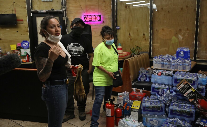 Volunteers with Security Latinos De La Lake secure a business as they work to protect homes and businesses during continued demonstrations over the death of George Floyd, an African American man, by a Minneapolis police officer.