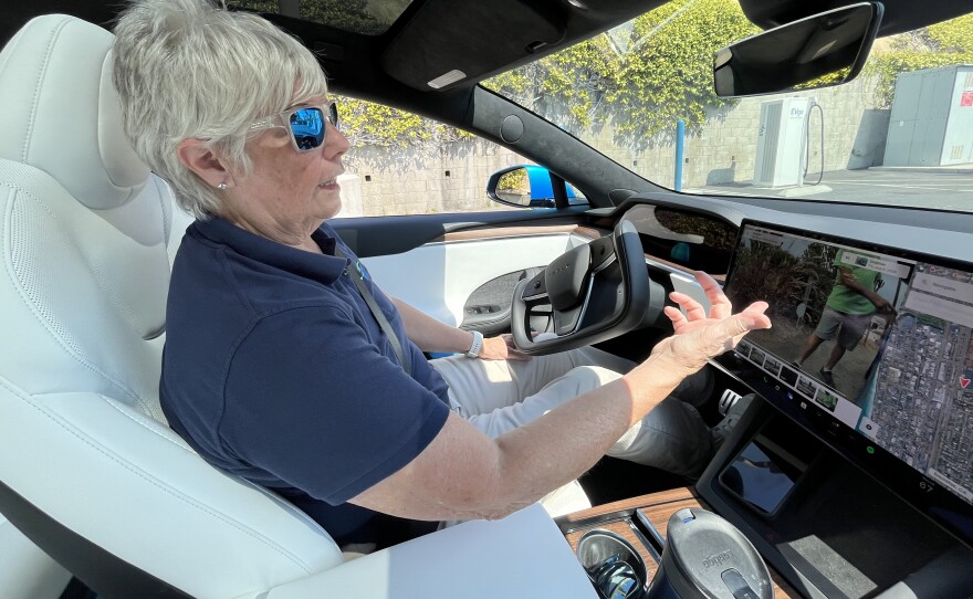Elaine Borseth explains some of her car's functions while driving inside her fully-electric Model S Tesla, Aug. 10, 2025.