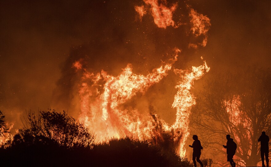 Motorists on Highway 101 watch flames from the Thomas fire leap above the roadway north of Ventura, Calif., on Wednesday.