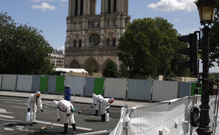 A cleanup crew scrubs pavement in front of the cathedral on Monday, after French inspectors said workers could return to the fire-damaged site to continue repairs.