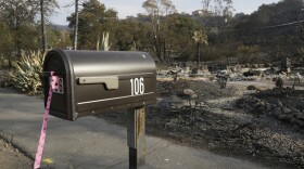 A mailbox, one of few items left at the site of the destroyed home in Napa, Calif., where Sara and Charles Rippey died in a fast-moving wildfire, shows a pink and black polka dot ribbon that indicates a fire crew has visited the location, Oct. 16, 2017. 