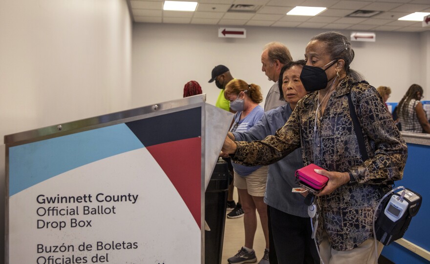 Gwinnett County voter Marian McCray (right) receives help from a poll worker while dropping off her absentee ballot at the Gwinnett County Board of Voter Registrations and Elections, in Lawrenceville, Ga., on May 18.