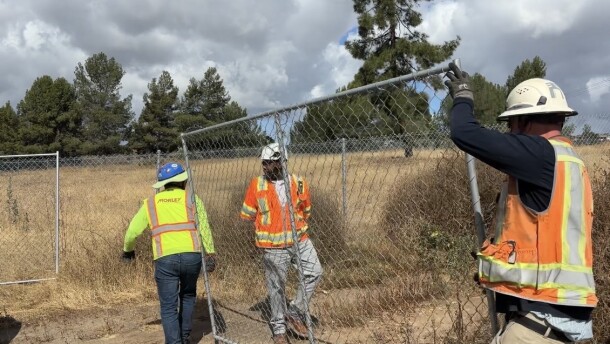 Construction workers unload fencing from a truck at the corner of Troy Street and Sweetwater Road on April 27, 2026.