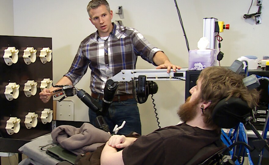 Robert Gaunt tests Nathan Copeland's ability to detect touch by tapping fingers on a robotic hand.