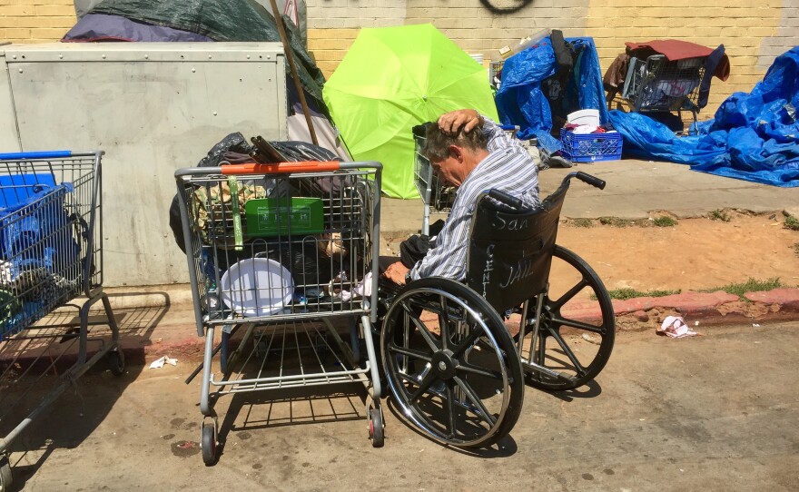 A man sits in a wheelchair near homeless encampments on 17th Street in San Diego's East Village, July 6, 2017.