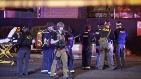 Police officers and medical personnel stand at the scene of a shooting near the Mandalay Bay resort and casino on the Las Vegas Strip, Monday, Oct. 2, 2017. 