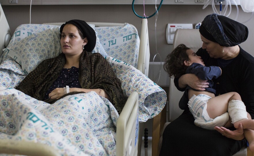 Odel Bennett, a 22-year-old Israeli woman, lies on a hospital bed as her mother Miriam Gal holds Odel's son Natan, 2, at the Hadassah Medical Center in Jerusalem. Bennett was stabbed in an Oct. 3 attack by a Palestinian that killed her husband and lightly wounded her son.