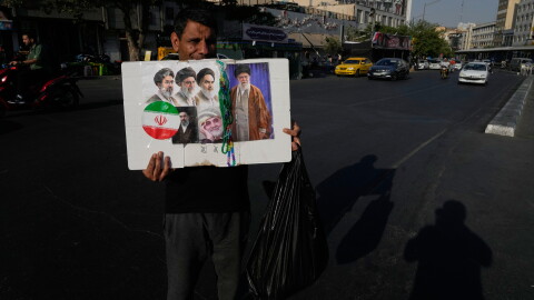 A man displays a placard with portraits of the current and late supreme leaders and the late Revolutionary Guard Gen. Qassem Soleimani at the Islamic Revolution Square in downtown Tehran, Iran, Saturday, July 18, 2026.