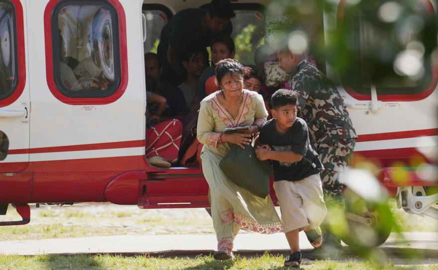 Army soldiers help a family disembark from a helicopter after they are rescued from an area affected by flash flooding in Nepal's Nuwakot district, Friday, Aug. 28, 2026.