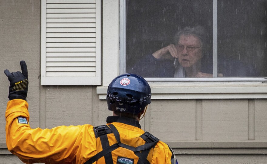 A Santa Rosa firefighter convinces a resident to evacuate after being trapped by floodwaters on Neotomas Ave. in Santa Rosa, Calif., Sunday.