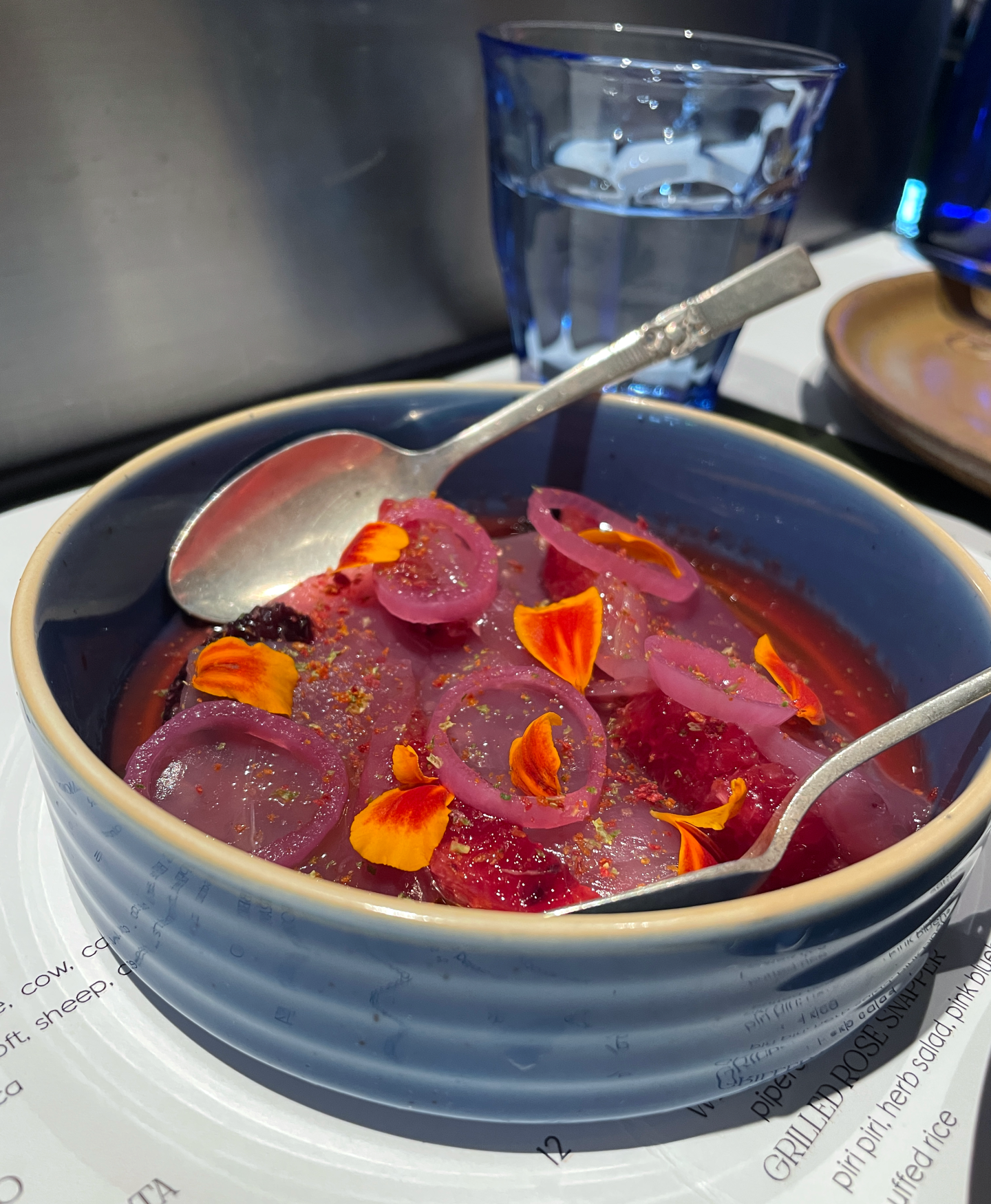 <b>Bluefin Tuna</b><br/>Line-caught bluefin served with pickled onions, blood orange, marigold flowers and a vibrant purple sauce made from dehydrated plum pulp. Mildly fruity, floral and summery.