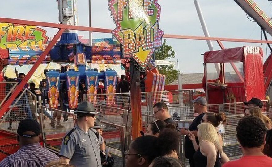 People watch as authorities respond after part of the Fire Ball ride broke off while in motion Wednesday night at the Ohio State Fair in Columbus, Ohio. One person was killed and several were critically injured.