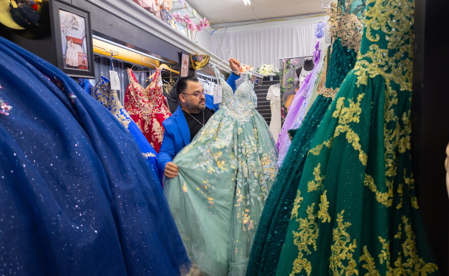 Osmar Naranjo hangs a quinceañera gown on a rack of gown in his shop Cynderella Brides in Chula Vista, April 30, 2026.