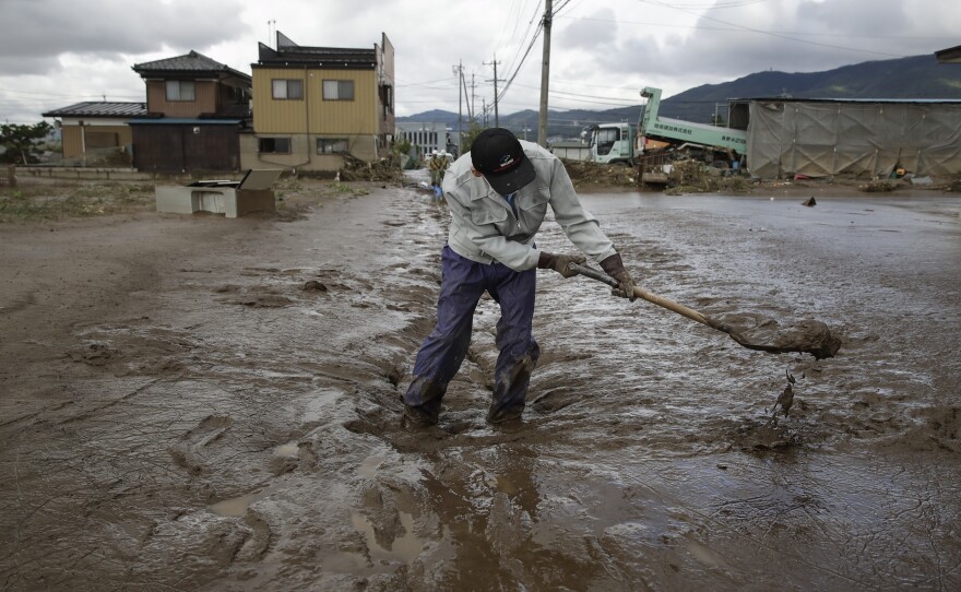 A man uses a shovel to scoop mud Tuesday in a neighborhood devastated by Typhoon Hagibis in Nagano, Japan.