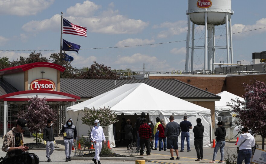 Workers line up to enter a Tyson Foods pork processing plant last month in Logansport, Ind. Some of the worst workplace coronavirus outbreaks have been in the meatpacking industry. Major meatpackers JBS USA, Smithfield Foods and Tyson have said worker safety is their highest priority.