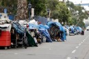 Homeless people stand among their items along 17th Street in San Diego, Sept. 19, 2017. 