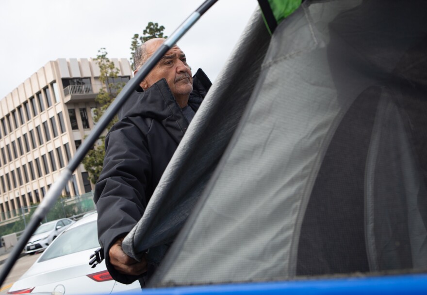 Martin Vasquez adjusts his tent in an effort to keep his tent dry in the rain, San Diego, March 30, 2023.