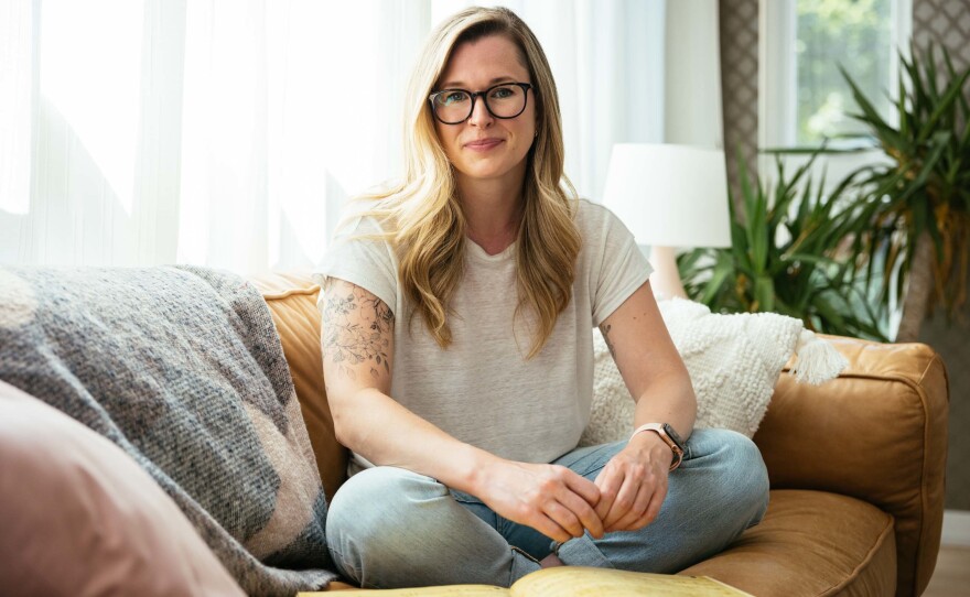 Software engineer Carla Stickler sits with her "Grimmerie," a behind-the-scenes book about <em>Wicked</em>, at her home on June 29 in Chicago. Stickler worked as a Broadway performer, appearing in <em>Wicked</em> as an ensemble member and understudy for Elphaba.