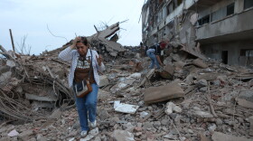 Residents walk among the rubble of building damaged in earthquakes the previous day in Catia La Mar, Venezuela