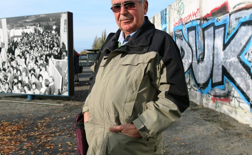 Jaeger stands in front of a remnant of the Berlin Wall. Behind him is a photo from Nov. 9, 1989, when he was the border guard who opened up the Bornholmer Street crossing, allowing East Germans to go to the west, the event that marked the fall of the wall.