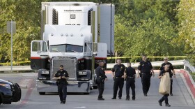 San Antonio police officers investigate the scene where eight people were found dead in a tractor-trailer loaded with at least 30 others outside a Walmart store in stifling summer heat in what police are calling a horrific human trafficking case, Sunday, July 23, 2017. 
