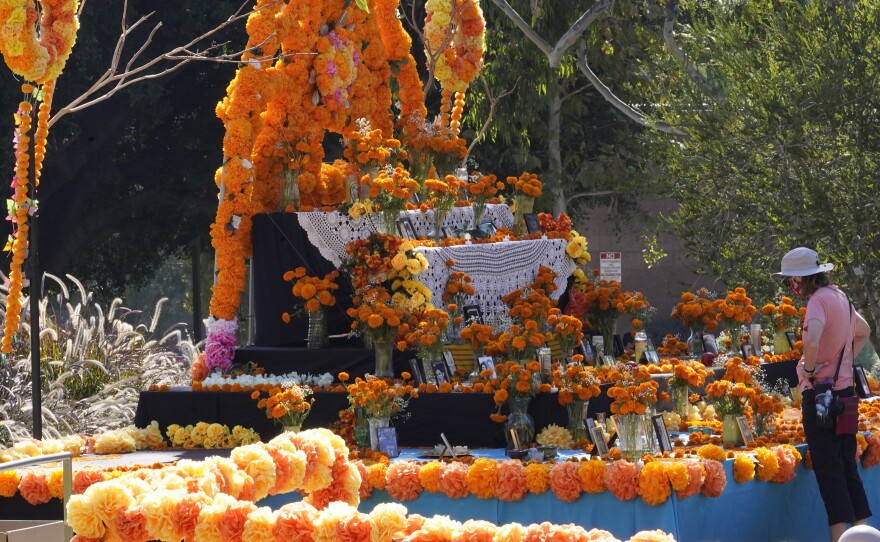 People visit a community altar decorated with marigolds at Grand Park in Los Angeles. Mother and daughter Chicana artists Ofelia and Rosanna Esparza have overseen the design of the altar at Grand Park since 2013. It's one of 11 huge altars done in a collaboration between Grand Park and Self Help Graphics, an organization highlighting Chicano and Latino artists and social justice.