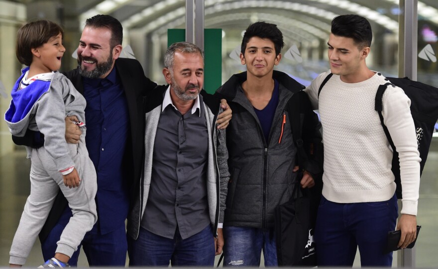 Syrian refugee Osama Abdul Mohsen, middle, is greeted as he arrives in Madrid in September with sons Zaid, far left, and Mohammad, second from right. Mohsen was tripped by a camerawoman as he scrambled across a field on the Serbia-Hungary border last fall. That incident was seen worldwide, and resulted in a job offer in Spain where he now coaches soccer.