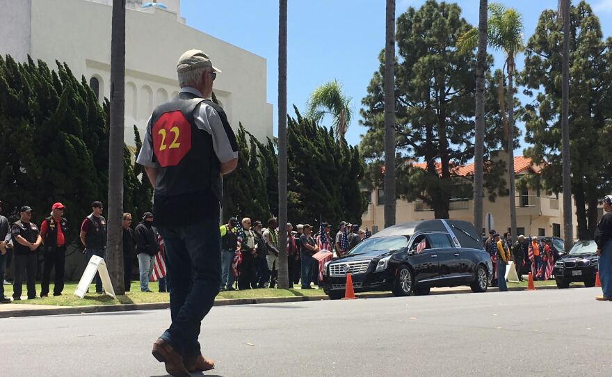 A man stands on a street in Coronado during a procession in honor of Charles Keating IV, May 13, 2016.