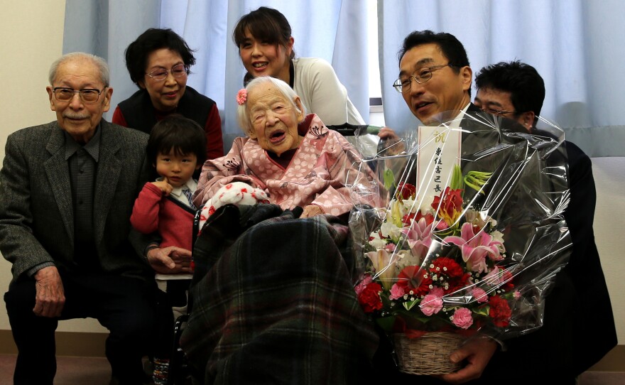 Misao Okawa, the world's oldest living person, poses for a photo with her son Hiroshi Okawa, 92, left, and other family members and friends on her 117th birthday celebration at Kurenai Nursing Home in Osaka, Japan.