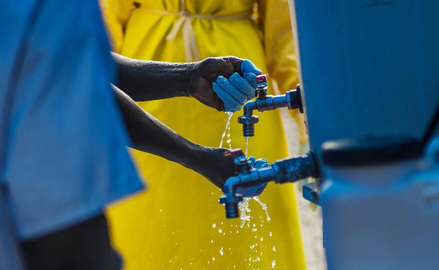 A health worker in Liberia washes up after leaving a clinic's Ebola isolation area.