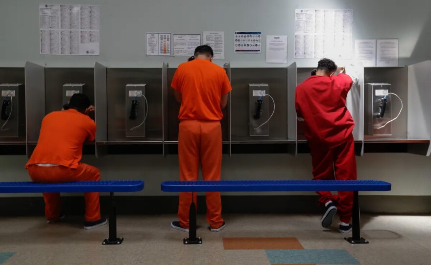 Detainees talk on telephones at the Adelanto ICE Processing Center in Adelanto on Aug. 28, 2019.